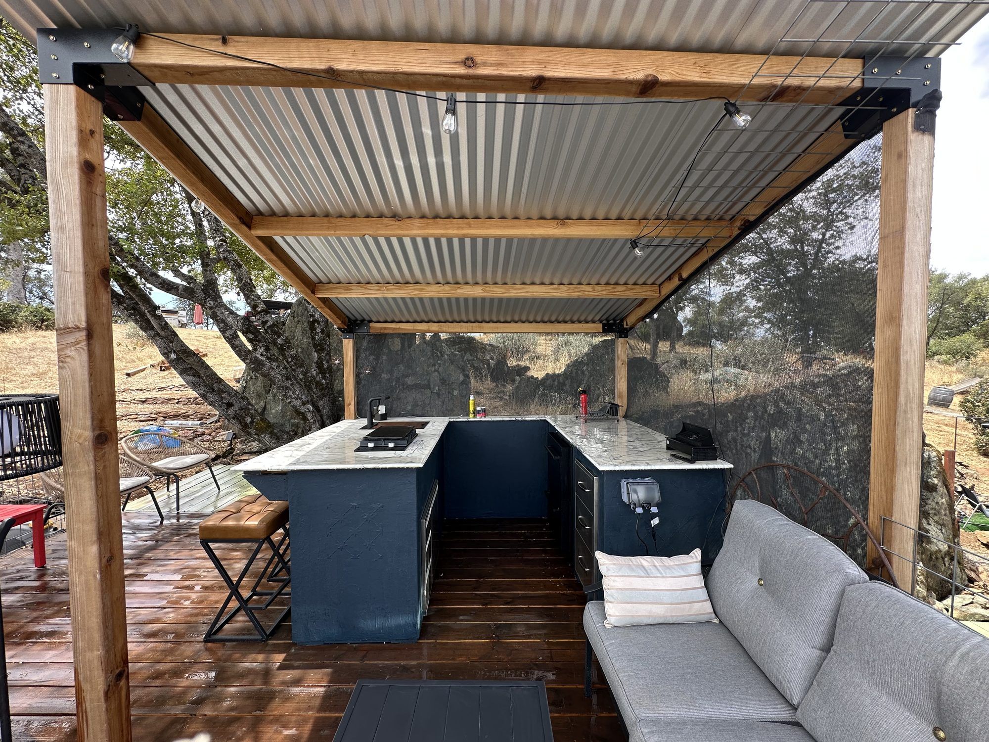 An outdoor kitchen area with a built-in counter, seating, and a pergola overhead.
