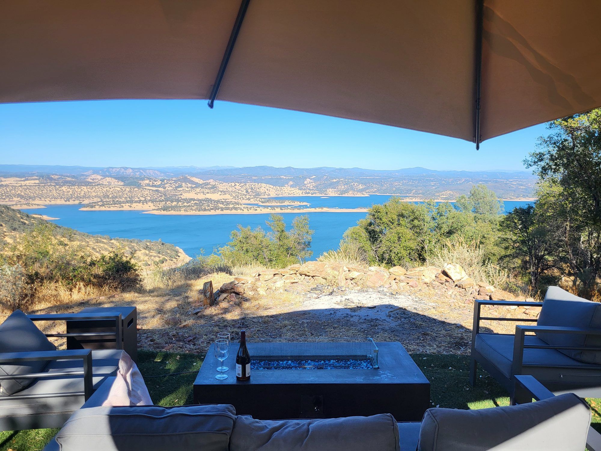 A covered outdoor seating area with a view of a lake and hills.