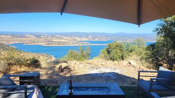 A covered outdoor seating area with a view of a lake and hills.