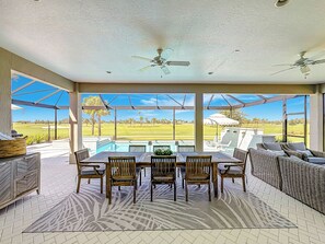 Ein überdachter Außenbereich mit Pool, Esstisch, Stühlen und Loungemöbeln.