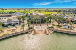 A waterfront property with a central circular staircase, a building with a glass facade, and a parking area. - Luxury Golf Front Retreat with Cascading Private Pool/Spa/Golf Cart (The Villages)