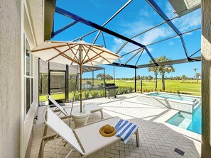 Un espace extérieur abrité comprenant une piscine, des chaises longues et un barbecue.
