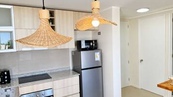 A modern kitchen with stainless steel appliances, light wood cabinetry, and two woven pendant lights.