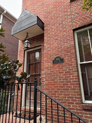 A brick building with a black awning, a black metal railing, and a door with a window. - Aspen Bend, a five bedroom retreat close to campus and town. (Oxford)