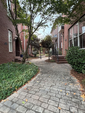 A brick building with a paved walkway, surrounded by greenery and trees. - Aspen Bend, a five bedroom retreat close to campus and town. (Oxford)