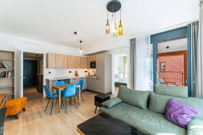 Un apartament modern amb zona de menjador, petita cuina i saló amb sofà i taula de centre.