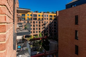 A multi-story building with a brick facade, a yellow building in the background, and a red pipe on the ground. - New  build Distillery Apartment by Rentez (Prague)