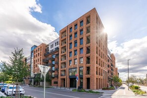 A multi-story building with a brick facade, multiple balconies, and a parking sign indicating a public parking area. - New  build Distillery Apartment by Rentez (Prague)