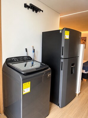 A compact kitchen with a washing machine and a refrigerator. - 402 - Air Conditioning • Balcony • 2 job openings | Near Laureles (Medellín)