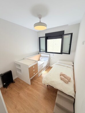 Une petite chambre comprenant un lit, un petit bureau et un radiateur.