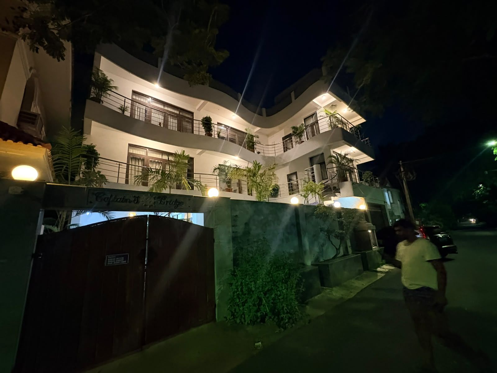 Um edifício com várias andares, varandas, portão e uma placa indicando um hotel.