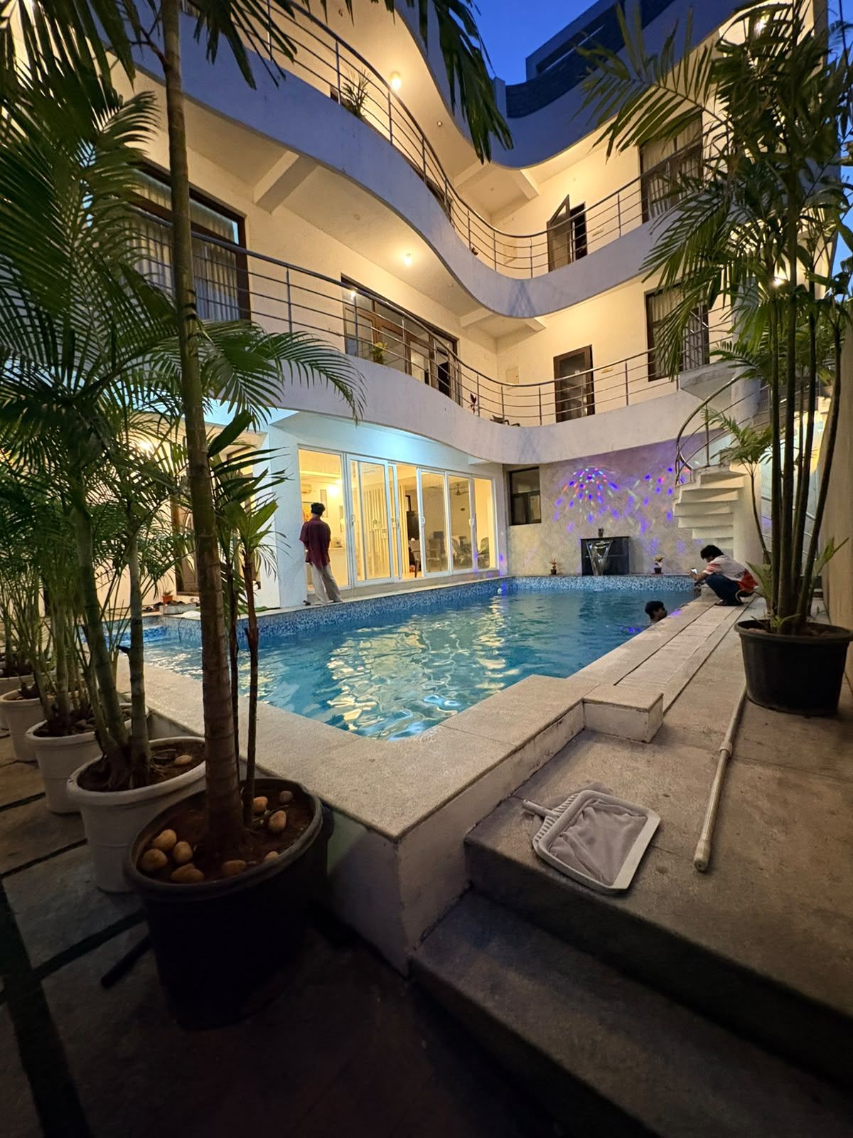 Ein mehrstöckiger, überdachter Swimmingpool mit einem gläsernen Bereich und Palmen.