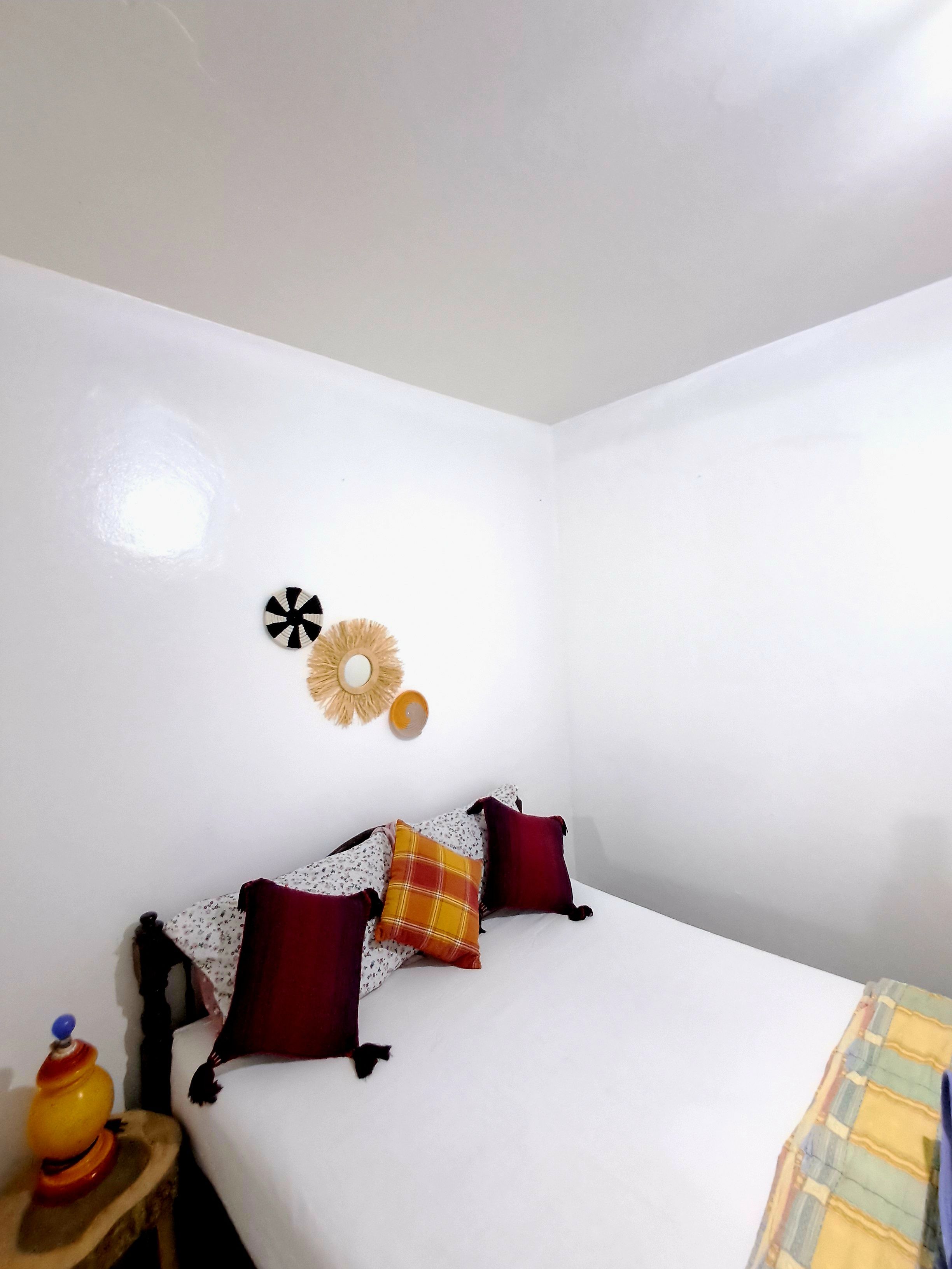 A bedroom with a bed, pillows, a wall clock, and a small table with a toy.