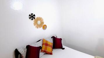 A bedroom with a bed, pillows, a wall clock, and a small table with a toy.
