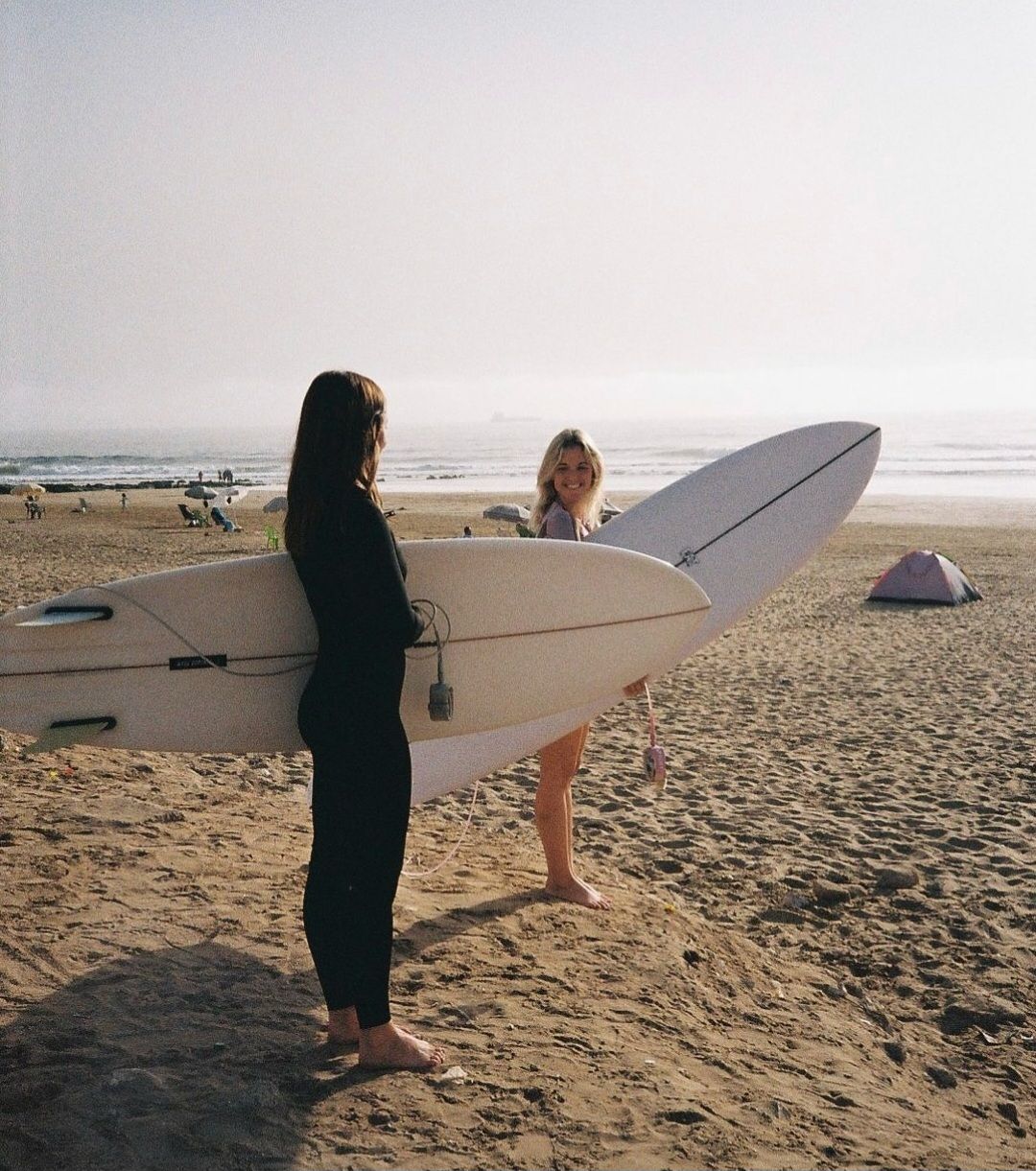 A beach scene with a person holding a surfboard.