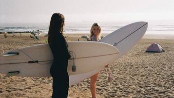 A beach scene with a person holding a surfboard.