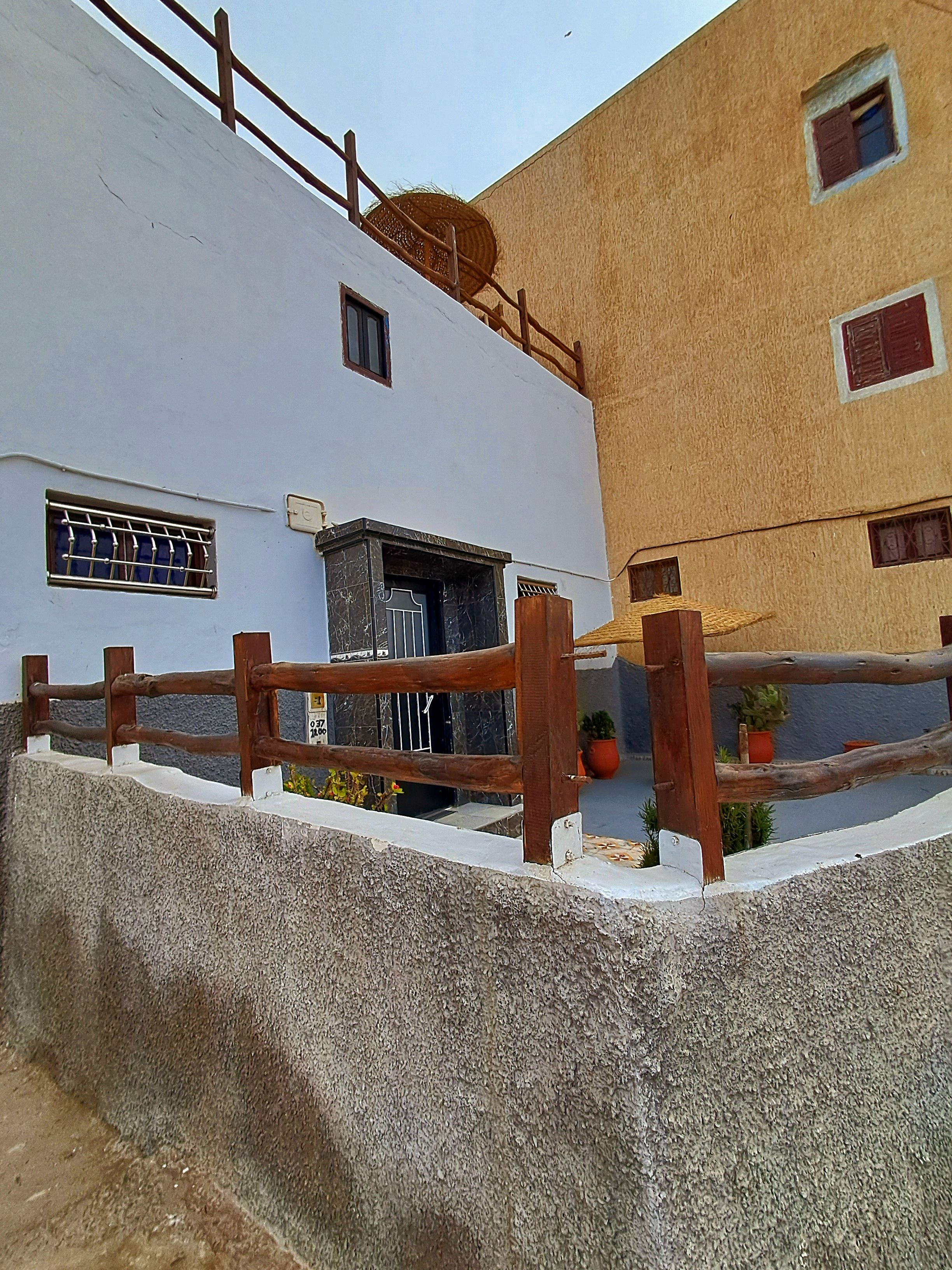 A building with a white facade, a wooden fence, and a small entrance with a door.