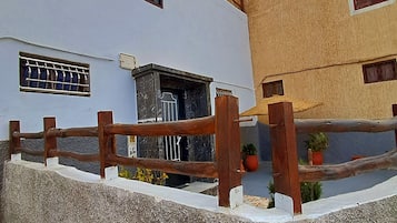 A building with a white facade, a wooden fence, and a small entrance with a door.