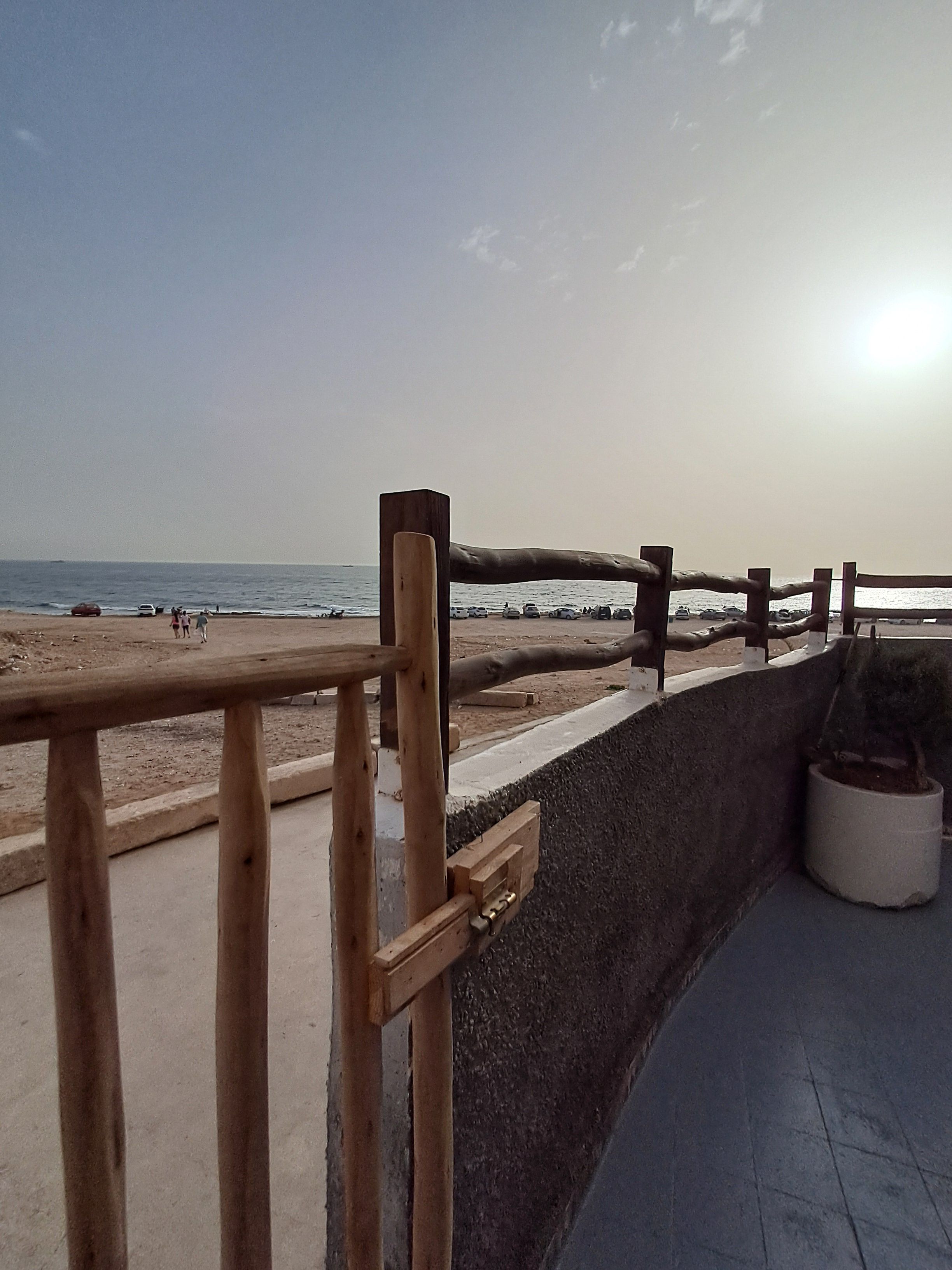 A wooden railing overlooking a beach with a clear sky.