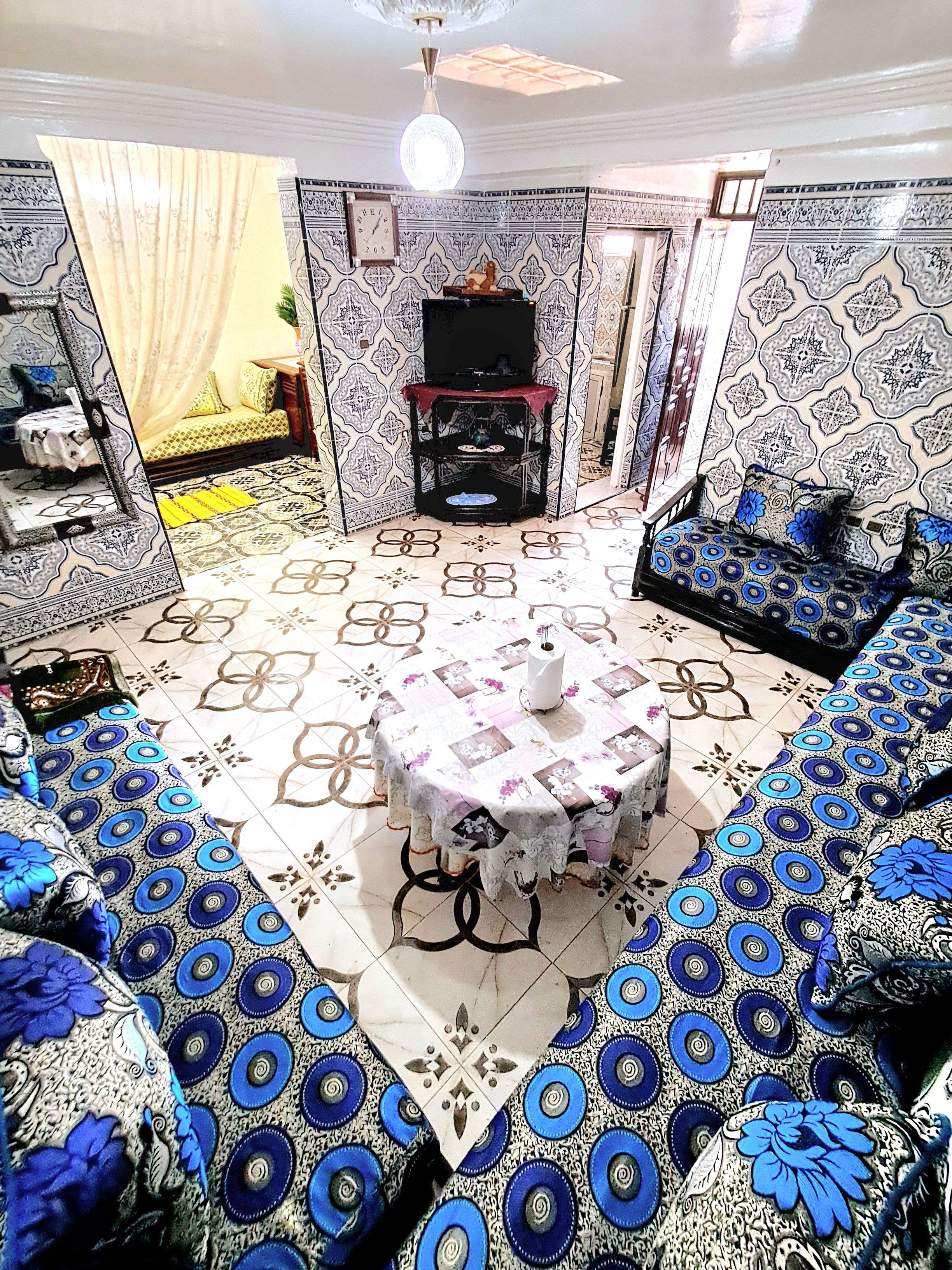 A room with a round table, patterned sofas, and a decorative cabinet.