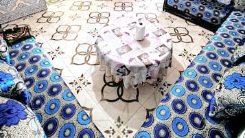 A room with a round table, patterned sofas, and a decorative cabinet.