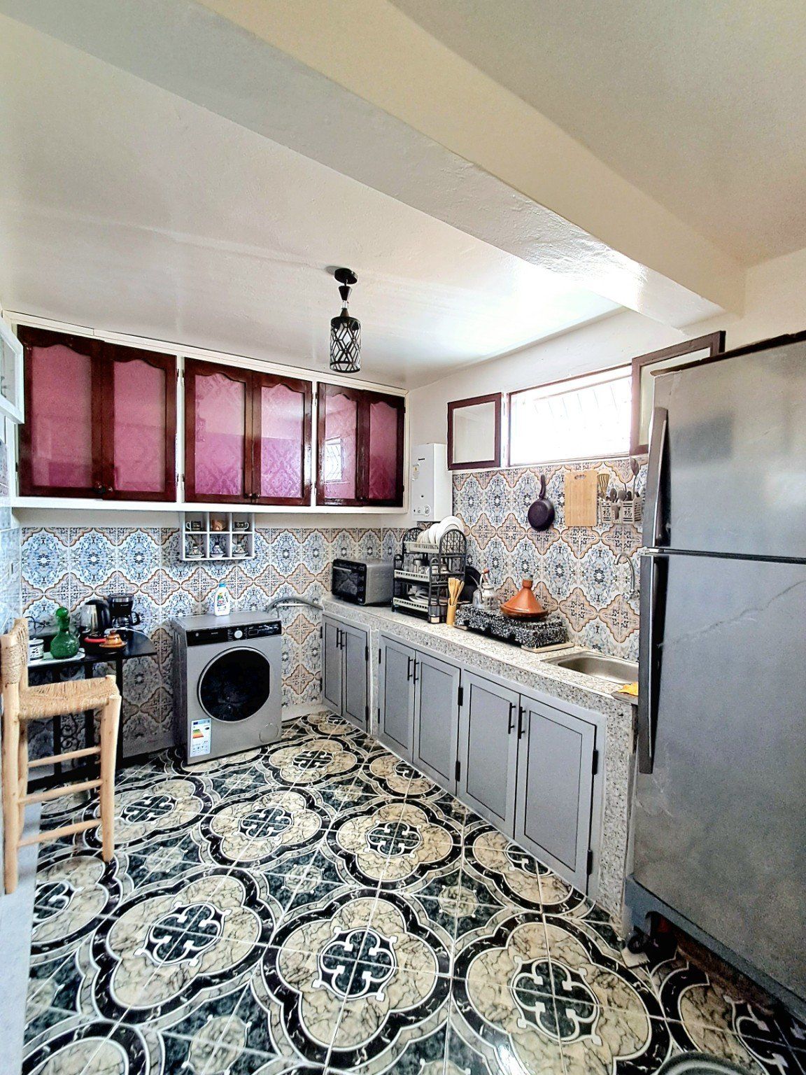 A compact kitchen with a washing machine, a refrigerator, and a microwave.