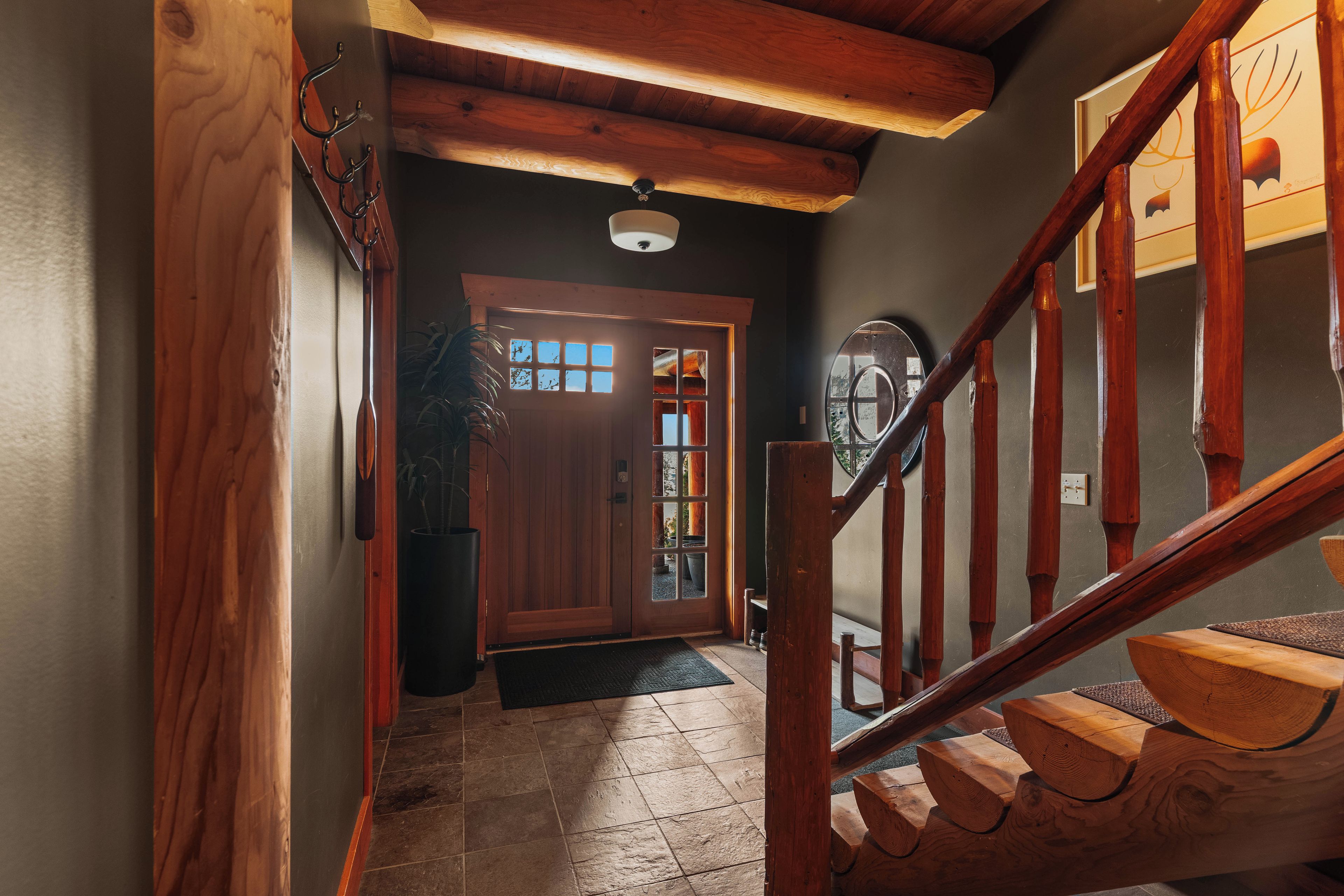 A wooden staircase leading to a door with a glass panel, a ceiling light, and a potted plant.