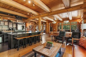 Una cocina amplia con una isla central, vigas de madera y un gran ventanal con vistas a la vegetación.