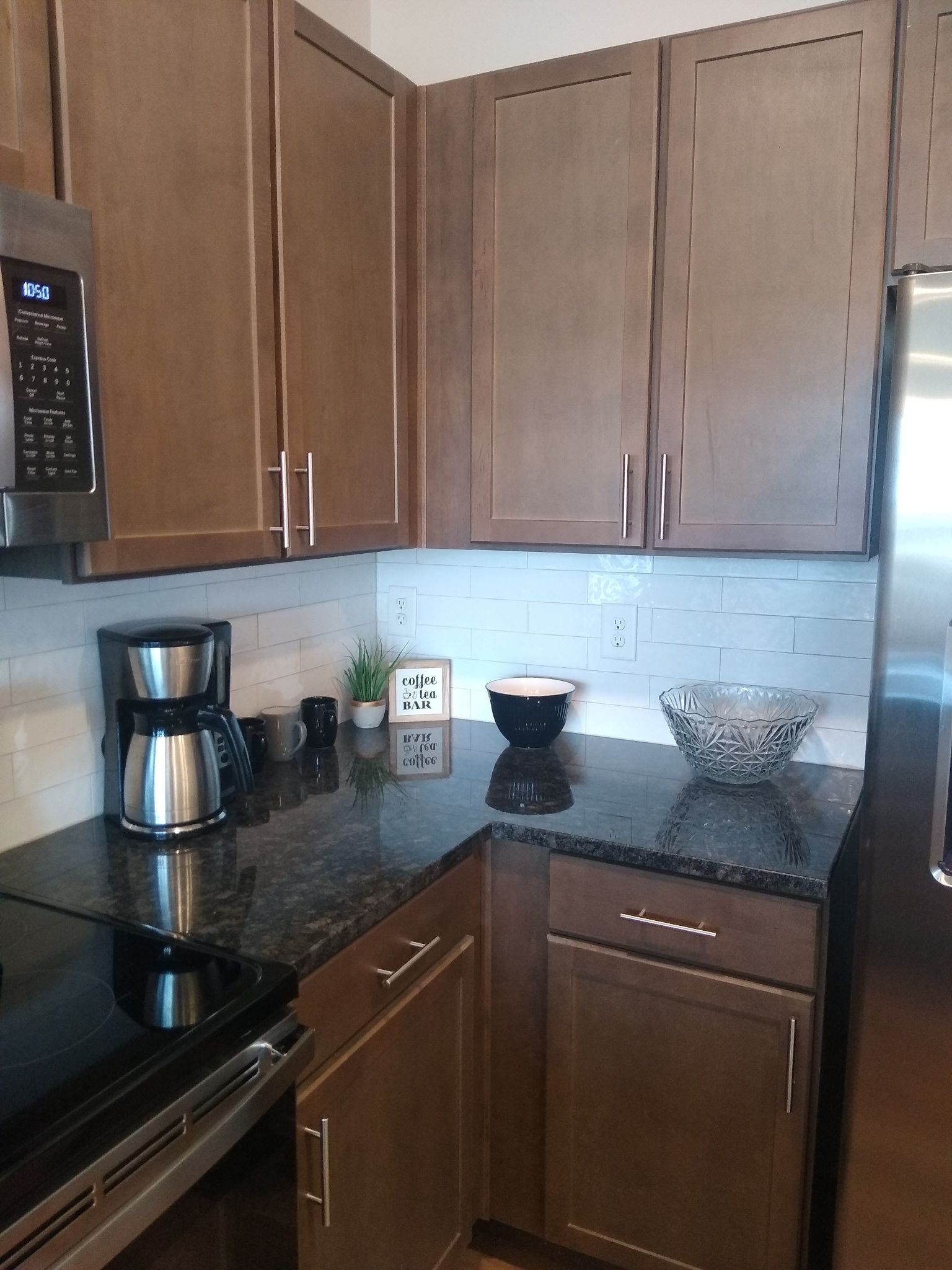 A kitchen with wooden cabinets, a stainless steel refrigerator, a coffee maker, and a microwave.