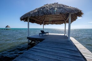 A wooden pier leading to a thatched-roof structure with a bench and a table. - LOWER Oceanfront Pool/kayak/paddleboard, caretaker (San Pedro)