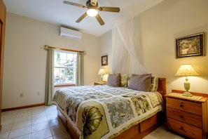 A bedroom with a bed, nightstands, a ceiling fan, a window with curtains, and a wall-mounted lamp. - LOWER Oceanfront Pool/kayak/paddleboard, caretaker (San Pedro)