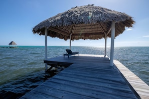 A wooden pier leading to a thatched-roof structure with a bench and a table. - Oceanfront Casita w/pool-kayaks-paddleboards-beach (San Pedro)