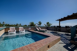 Un espace piscine aménagé sur le toit, avec des chaises longues et une pergola.