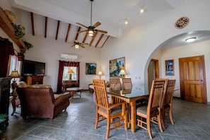 A spacious living area with a dining table, chairs, a television, and artwork on the walls. - Beachfront Estate pool/kayak/paddleboard Sleeps 12 (San Pedro)