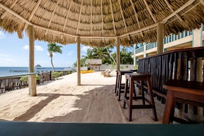 A beachside area with a thatched roof structure, wooden seating, and a view of the sea. - Beachfront Estate pool/kayak/paddleboard Sleeps 12 (San Pedro)