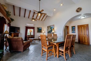 A spacious living area with a dining table, chairs, a television, and artwork on the walls. - UPPER 2BR/2BA Oceanfront w/Pool/kayak/paddleboards (San Pedro)