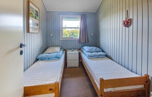 Allotjament petit d'una sola habitació amb dos llits búnquers de fusta, una finestra amb cortines i un quadre penjat a la paret.