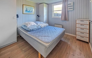 Un dormitorio con cama, ventana, radiador y unidad de almacenamiento.