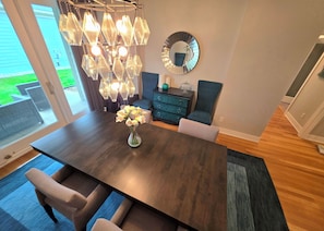A modern dining area with a dark wooden table, a vase of flowers, and a hanging light fixture. - Aspen Place | Zero-Step, 2 En-Suites, 1.5mi Mayo (Rochester)