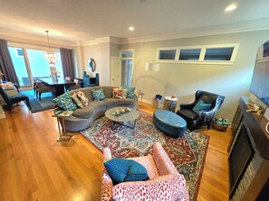 A living room with a sectional sofa, a round coffee table, a patterned rug, a fireplace, and a television. - Aspen Place | Zero-Step, 2 En-Suites, 1.5mi Mayo (Rochester)