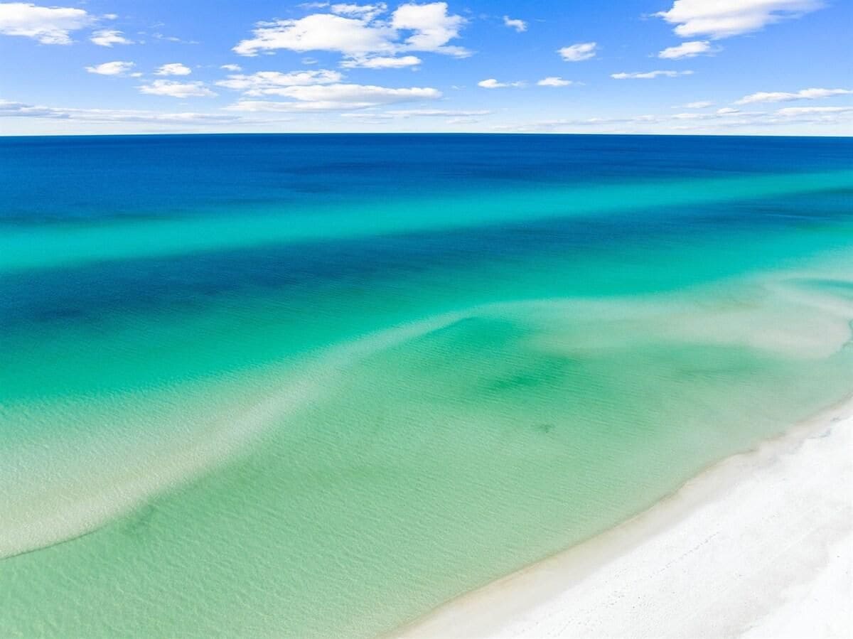 A beach with clear turquoise waters and a white sandy shore.