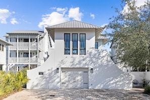 Ein modernes, zweistöckiges Haus mit Garage, Balkon und gepflasterter Auffahrt.