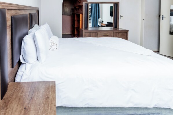 A neatly made bed with white linens in a hotel room.