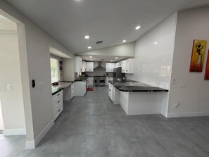 A modern kitchen with white cabinets, a central island, and a built-in oven. - Luxury 55+ Retreat  3BR/3BA  Golf & Resort Amen. (Las Vegas)