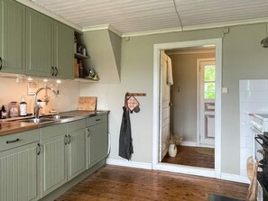 A kitchen with green cabinets, a wooden countertop, and a hanging towel. - 8 Person Holiday Home in Lottorp (Löttorp)