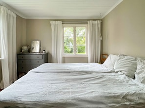 A bedroom with a bed, a dresser, a window with curtains, and a view of greenery outside. - 8 Person Holiday Home in Lottorp (Löttorp)