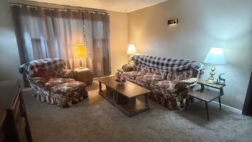 A living room with two armchairs, a sofa, a coffee table, and two lamps.