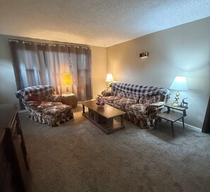 A living room with two armchairs, a sofa, a coffee table, and two lamps.