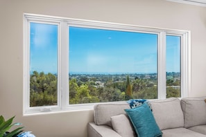 A room with a large window offering a view of a cityscape and greenery. - Furnished Penthouse for Medical, Corporate & Extended Santa Barbara Stays (Santa Barbara)