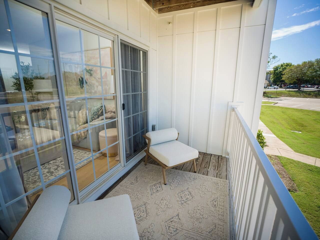 A balcony with a sliding glass door, a cushioned bench, and a patterned rug.